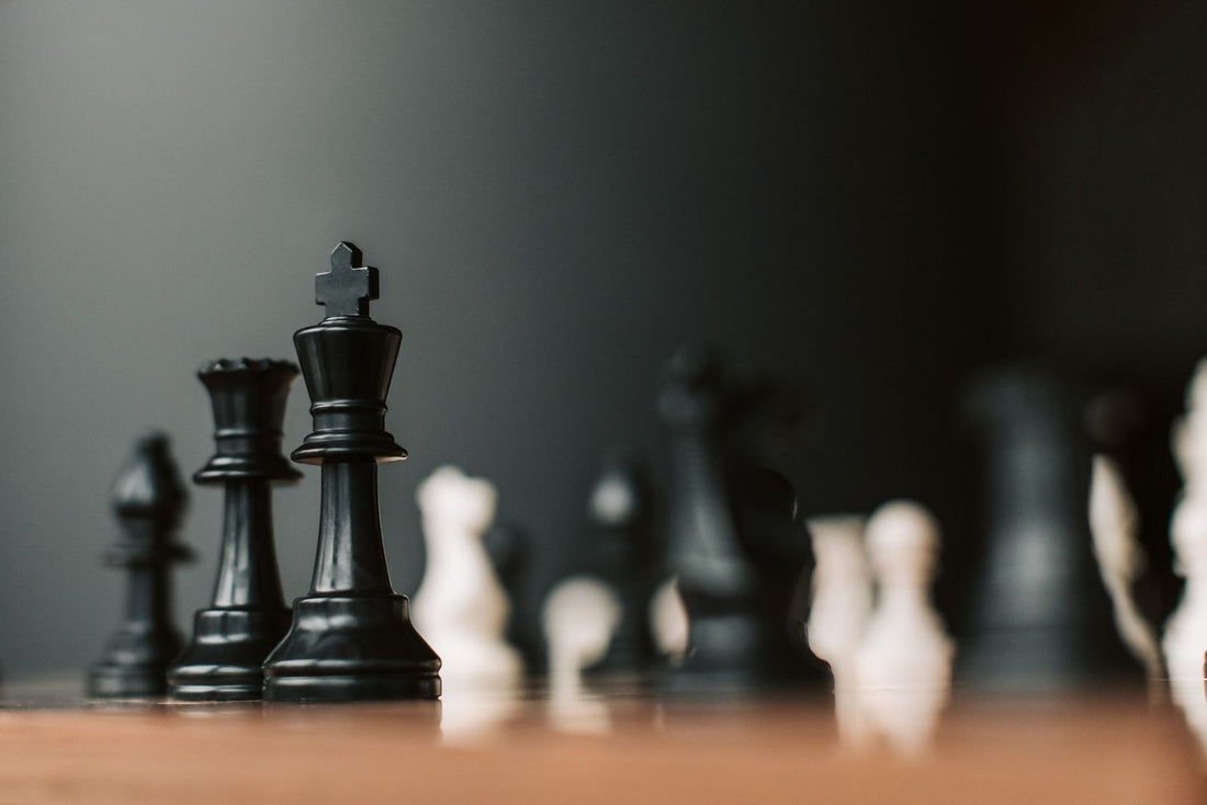 Black chess king standing tall on a board in low light