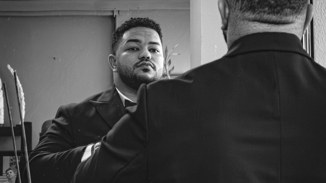 Man in a tailored suit studying his reflection in a mirror