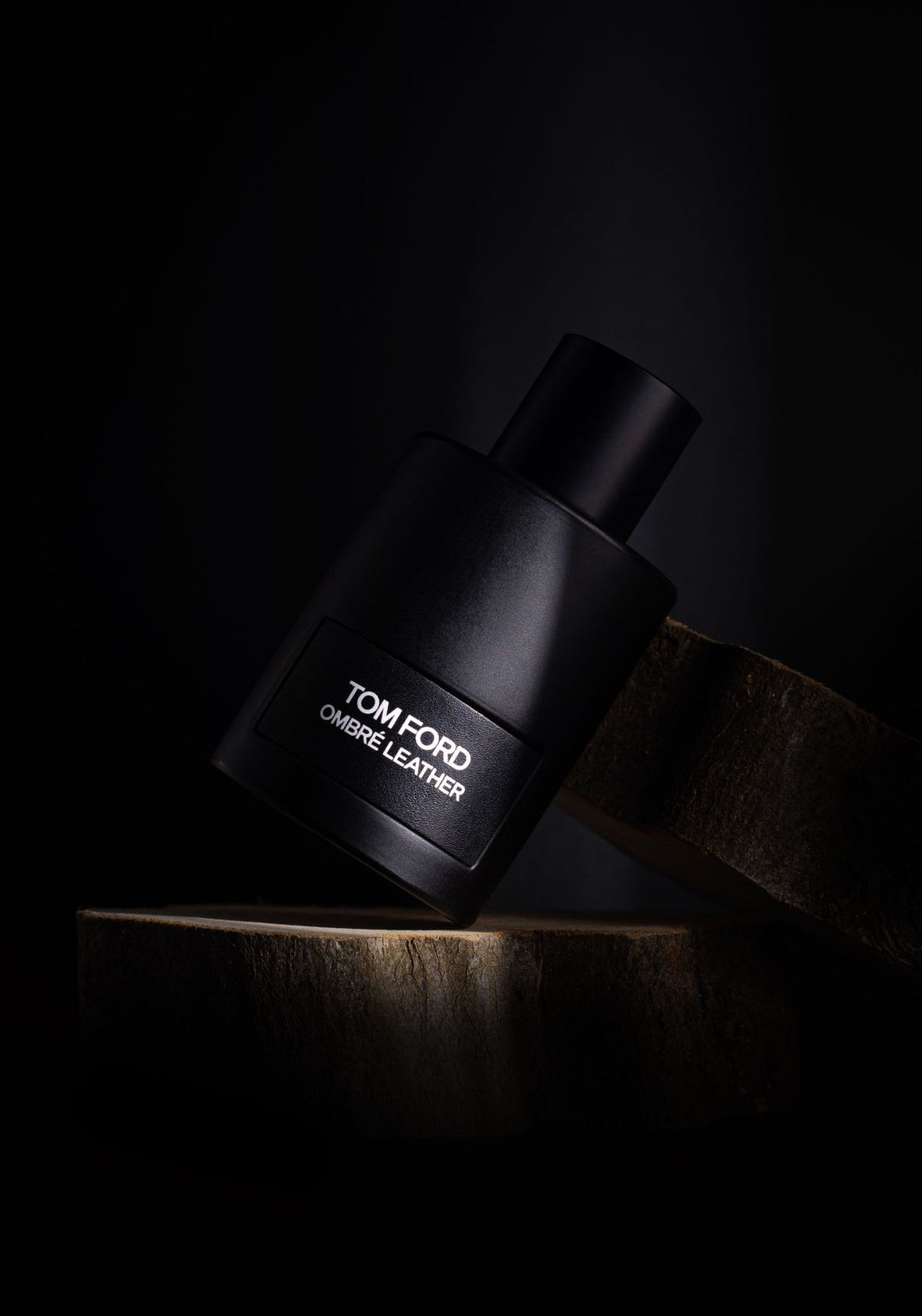 Elegant black fragrance bottle lit against a dark background in a premium editorial style