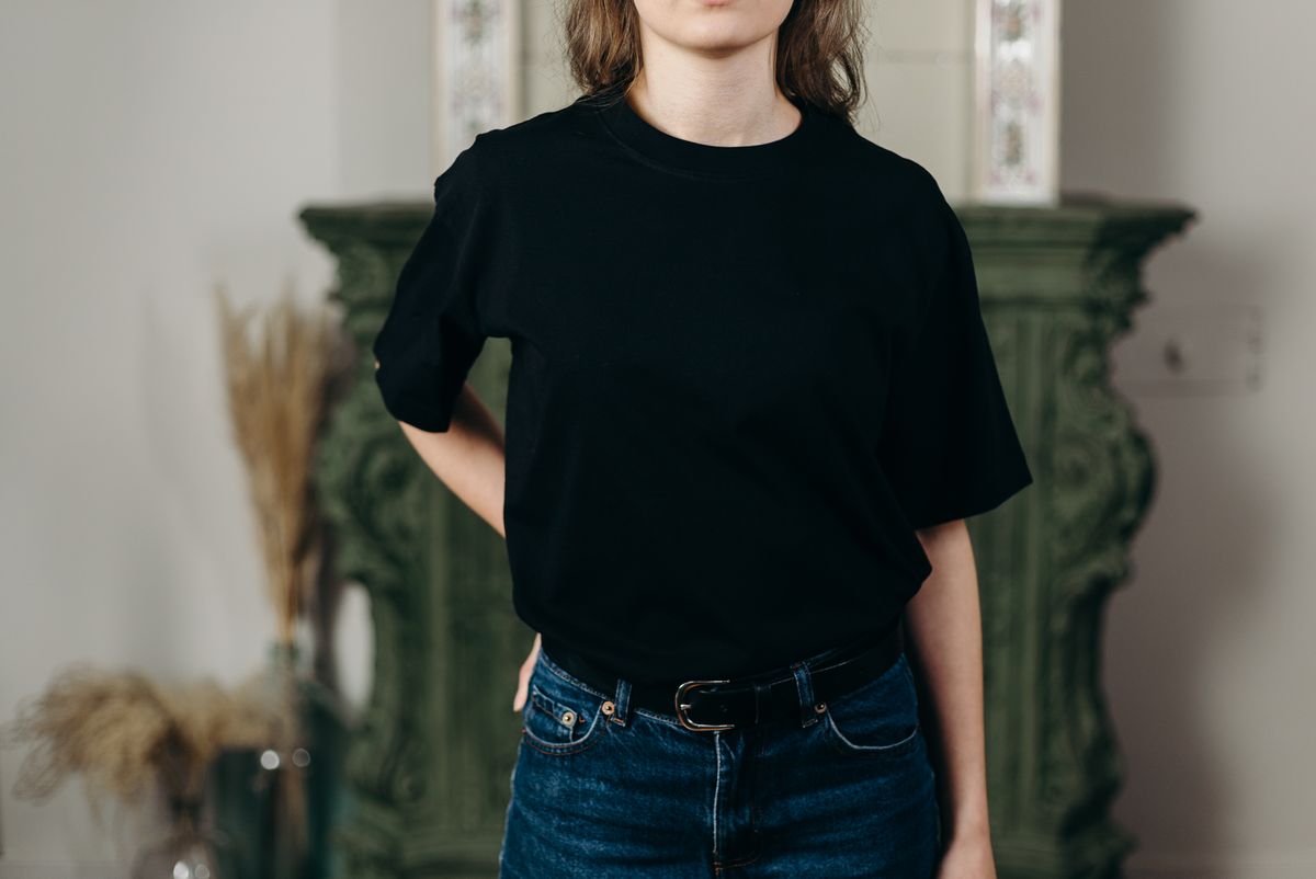 Man in a fitted black t-shirt and dark denim jeans against a plain studio backdrop