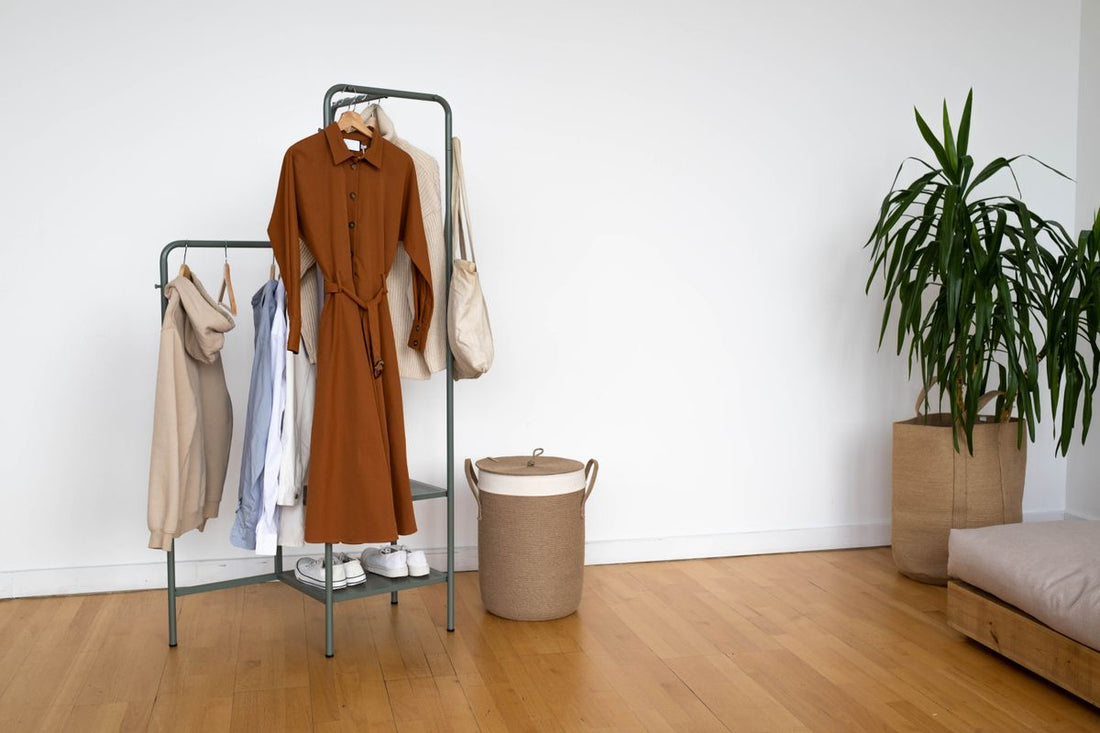 Neutral menswear hanging on a minimalist metal clothing rack in a modern room.