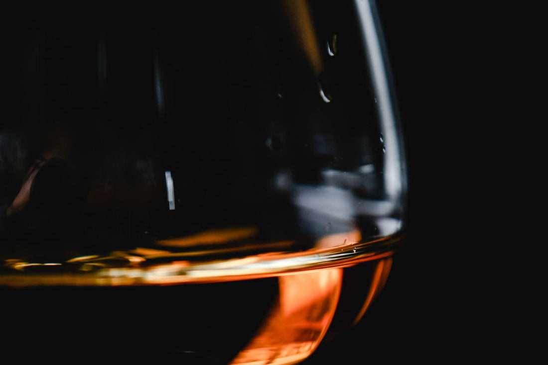 Glass of amber spirit glowing against a black background